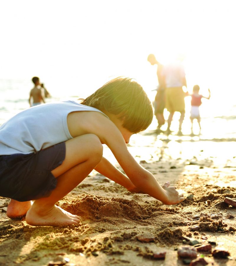 child digging in the sand at a beach