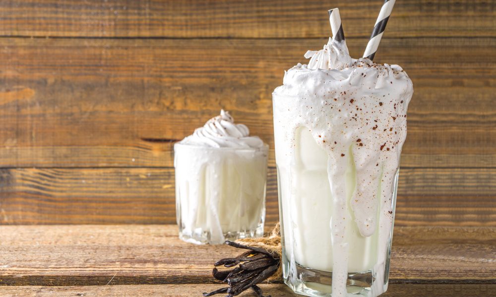 National Milkshake Day. A photo of two vanilla milkshakes / beverages with whipped cream on top.