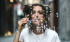 Young woman in a white T-shirt blowing colorful bubbles