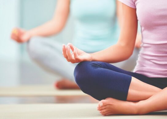 Image of the body of a woman sitting in a yoga pose with crossed legs