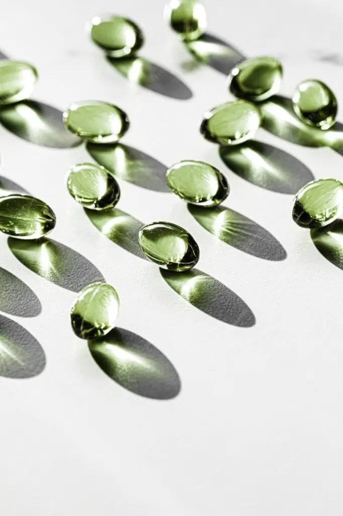 Green capsules with shadows on a white surface.