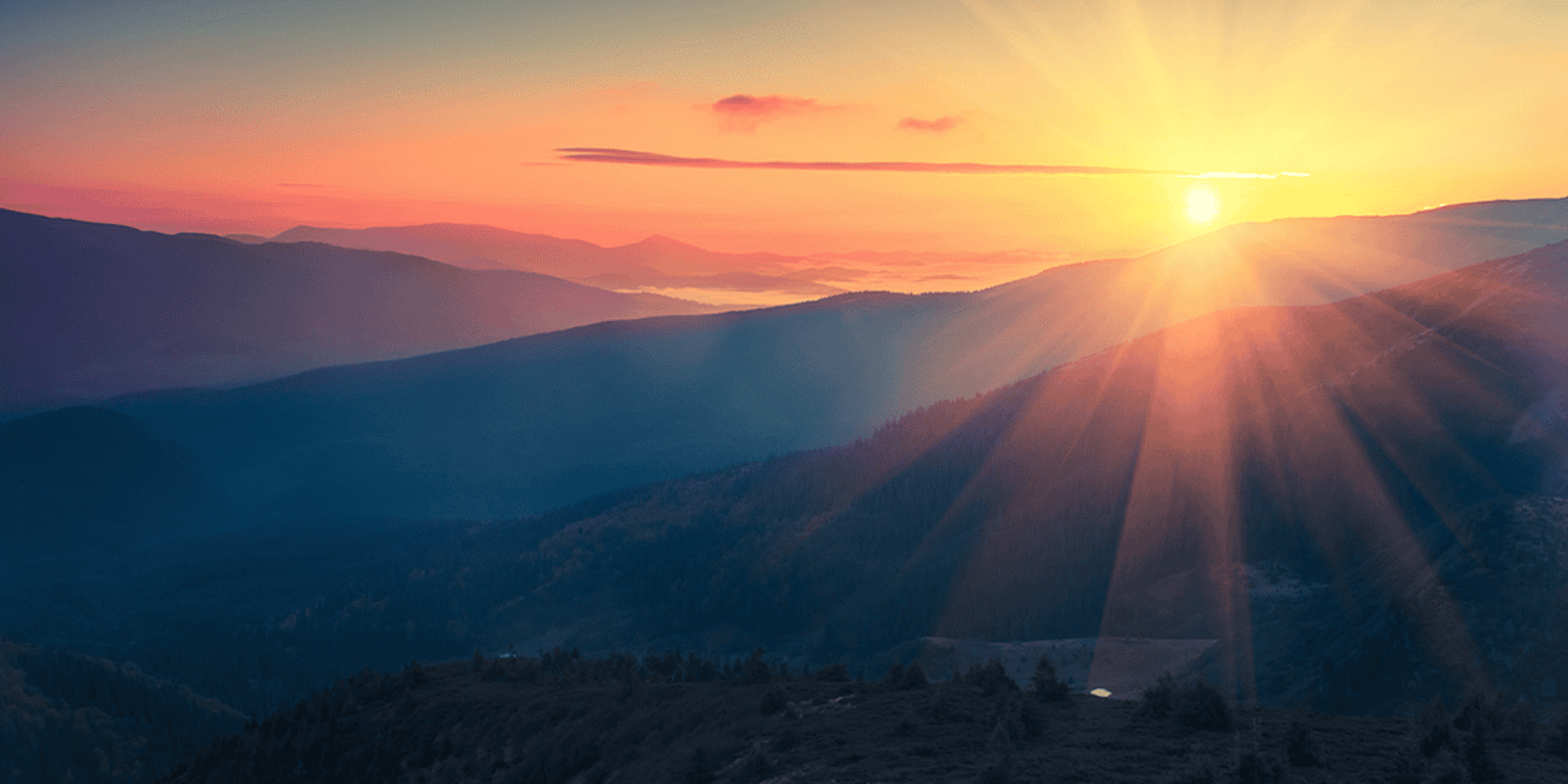 Sunrise over mountains with orange and pink sky.