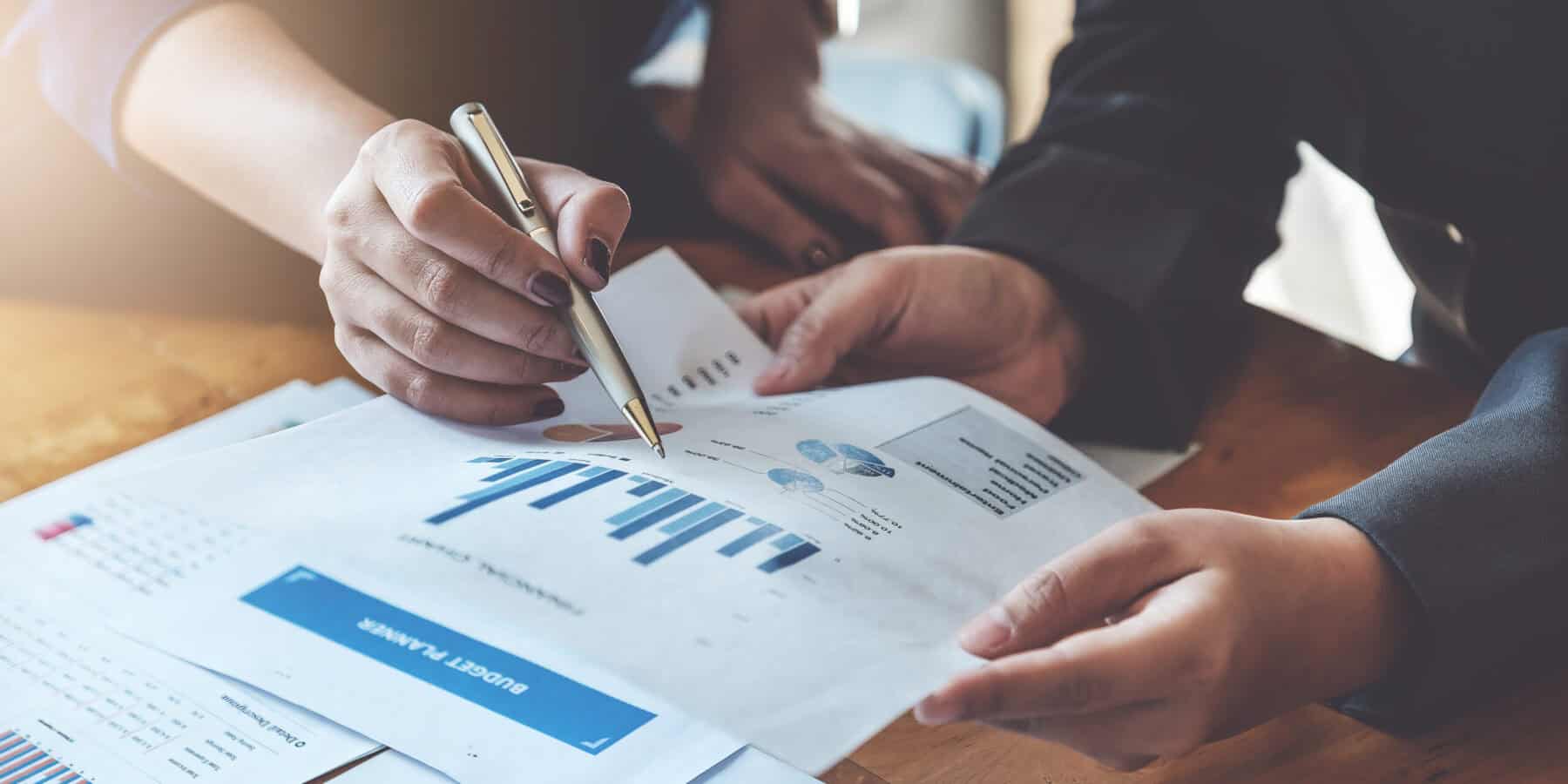 Business People Meeting to discuss and brainstorming the financial report paperwork in home office. Financial advisor teamwork and accounting concept. Two people analyzing financial charts at a desk.