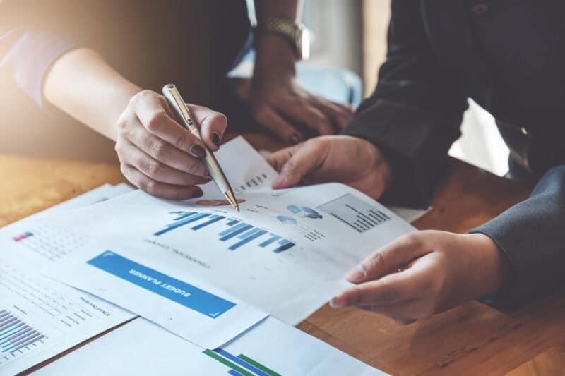 Two people analyzing financial charts at a desk.