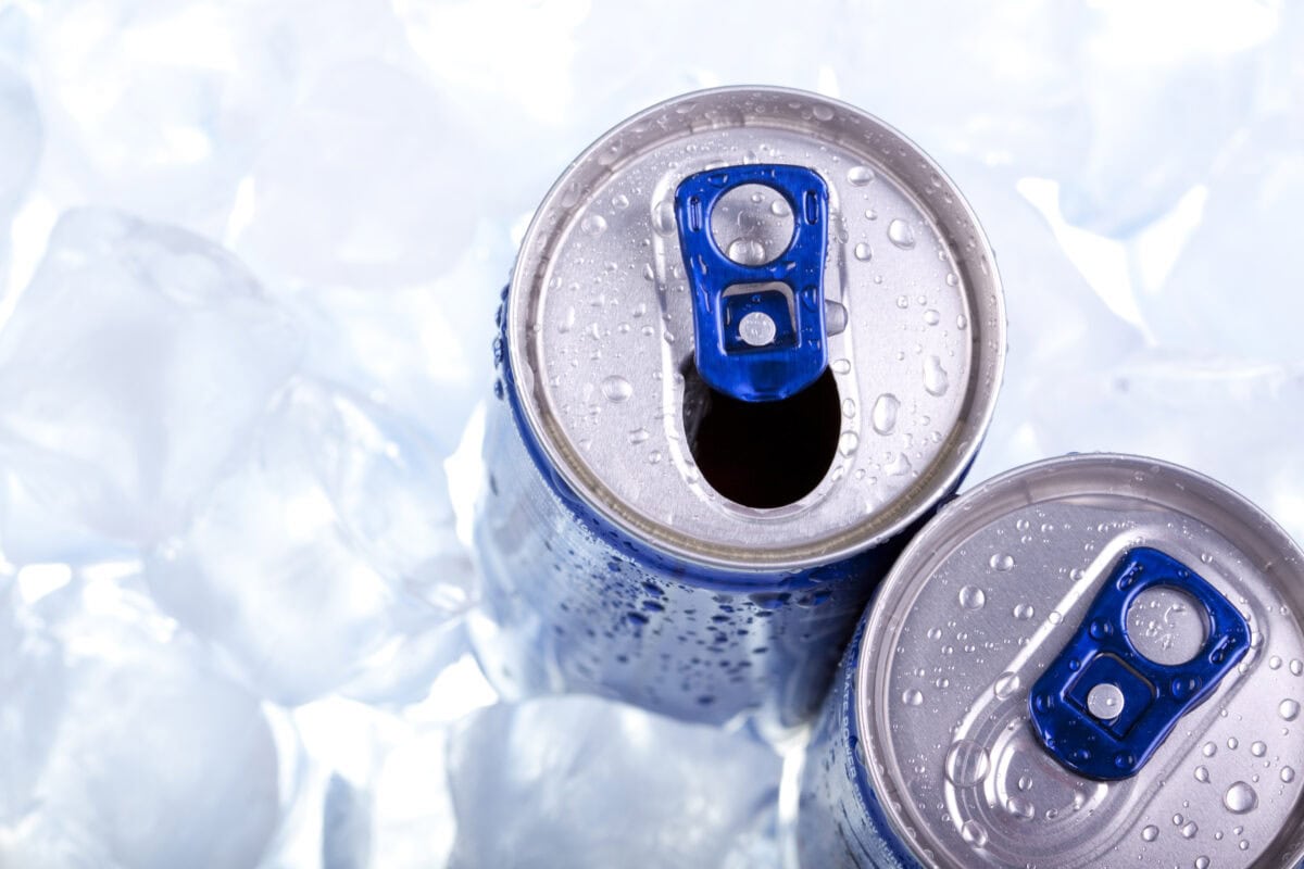 Energy Drink From The Top Two opened energy drink cans on ice with blue tabs.