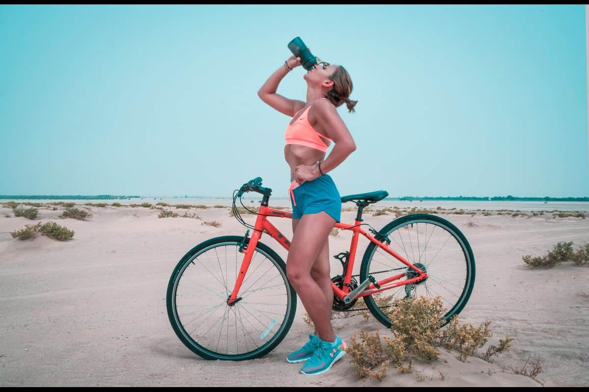 Fit woman on a bike drinking