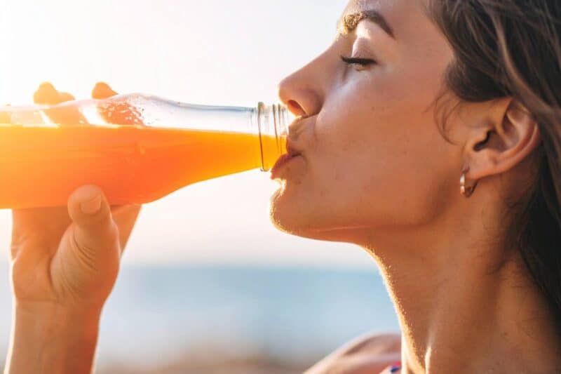 Image of a woman drinking out of a glass bottle