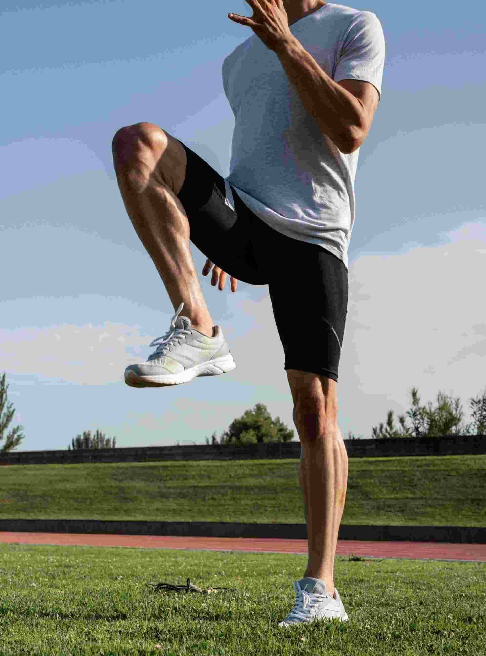 Individual performing a high-knee exercise during outdoor athletic training.