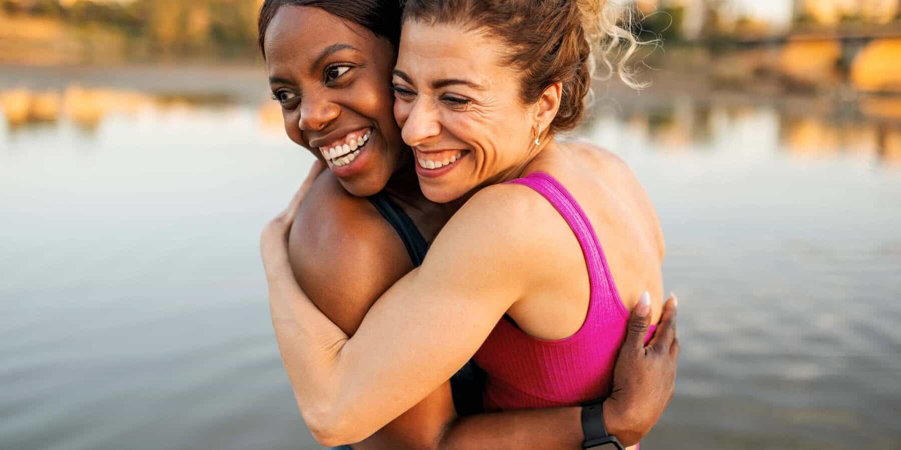 Two women hugging on the water