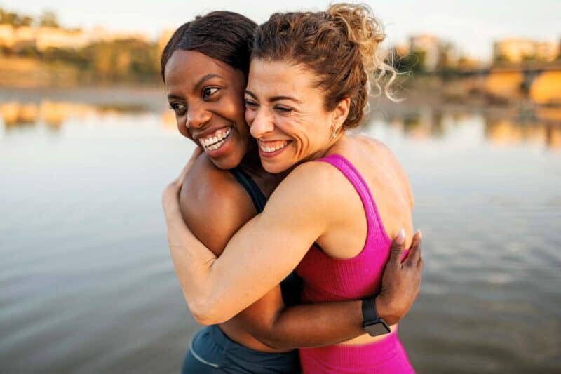 Two women hugging on the water