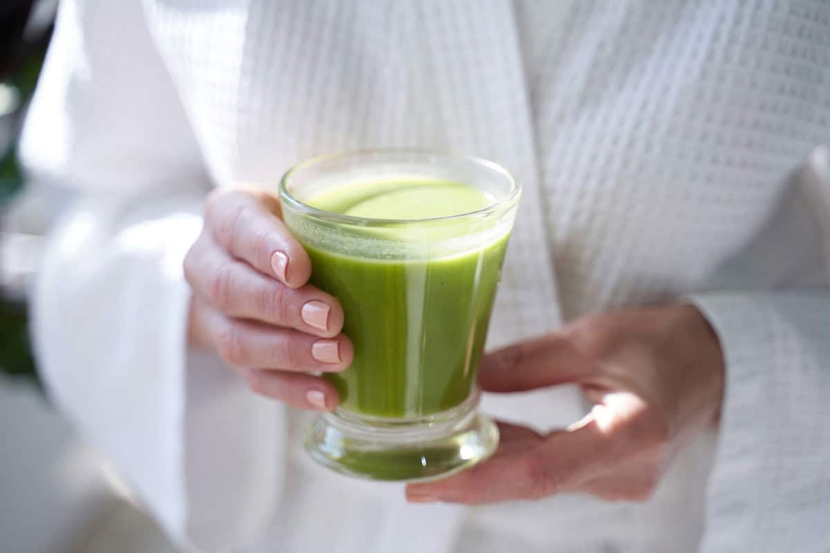 Drinks Image 1200x800px Image of a woman holding a green smoothie in a glass