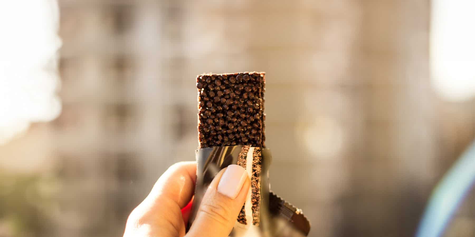 GLP 1 Balanced Snacking Hero Image 1800x900px Image of a person holding a protein bar