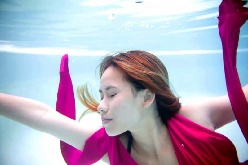Image of a woman swimming in a pool with a pink scarf
