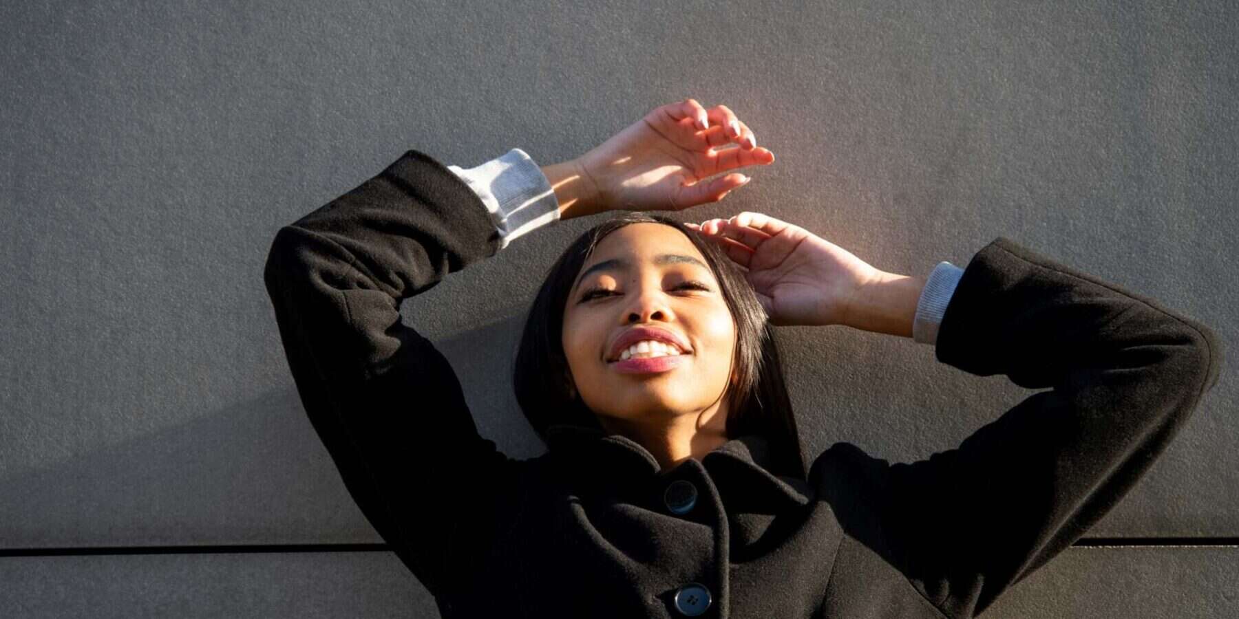 Image of a woman on her back with a black coat on.