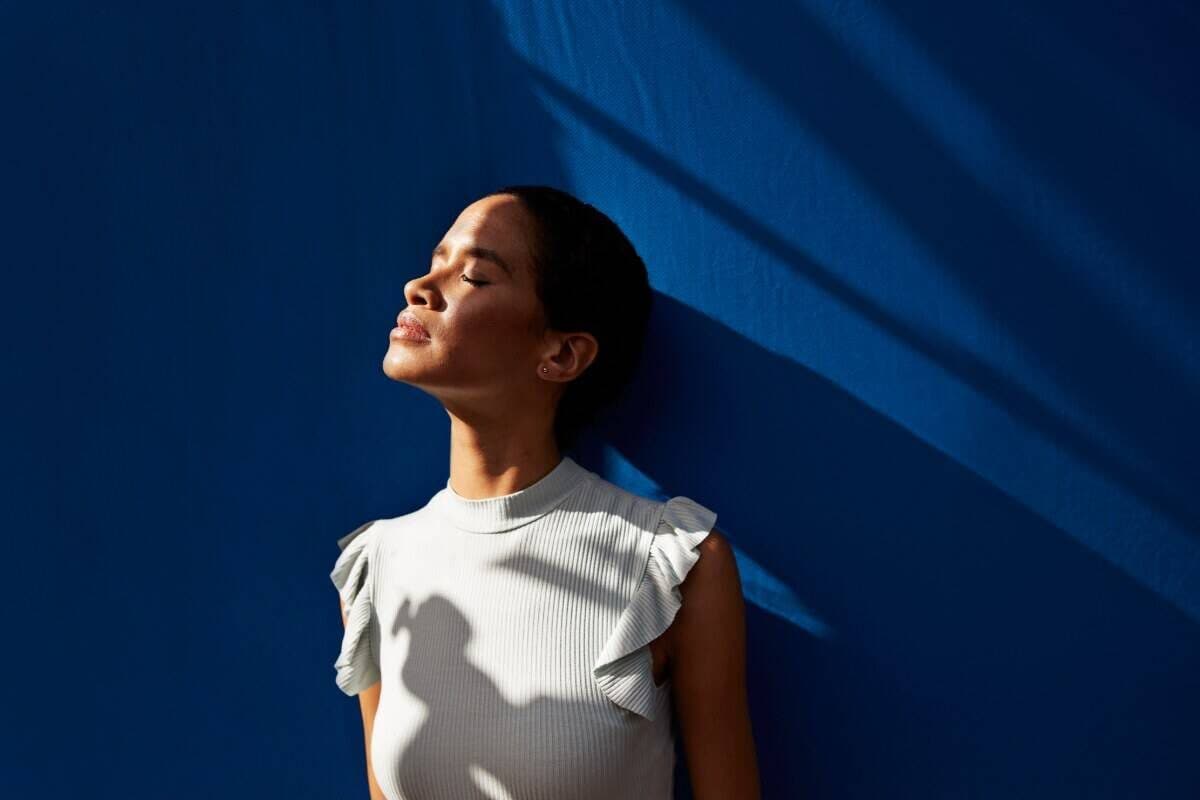 Person standing in natural sunlight against a blue wall, illustrating wellness topics related to magnesium and stress, magnesium and brain health, and magnesium mood support.