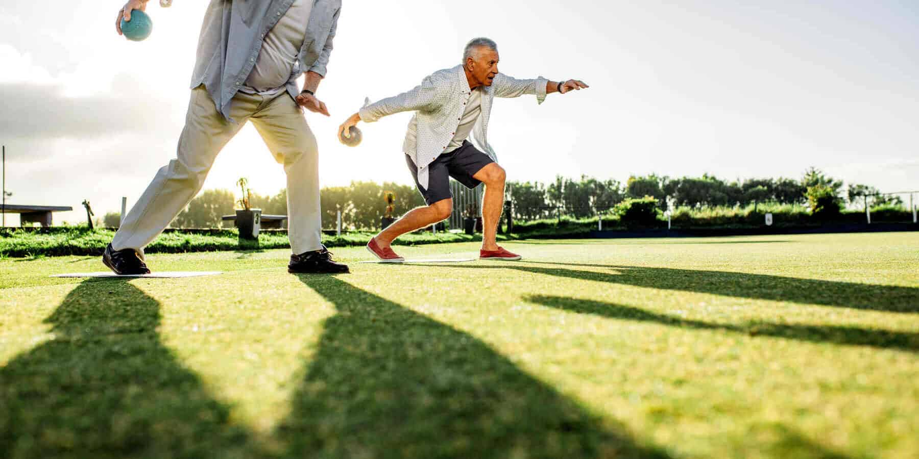 Image of two aging men playing bocce ball.