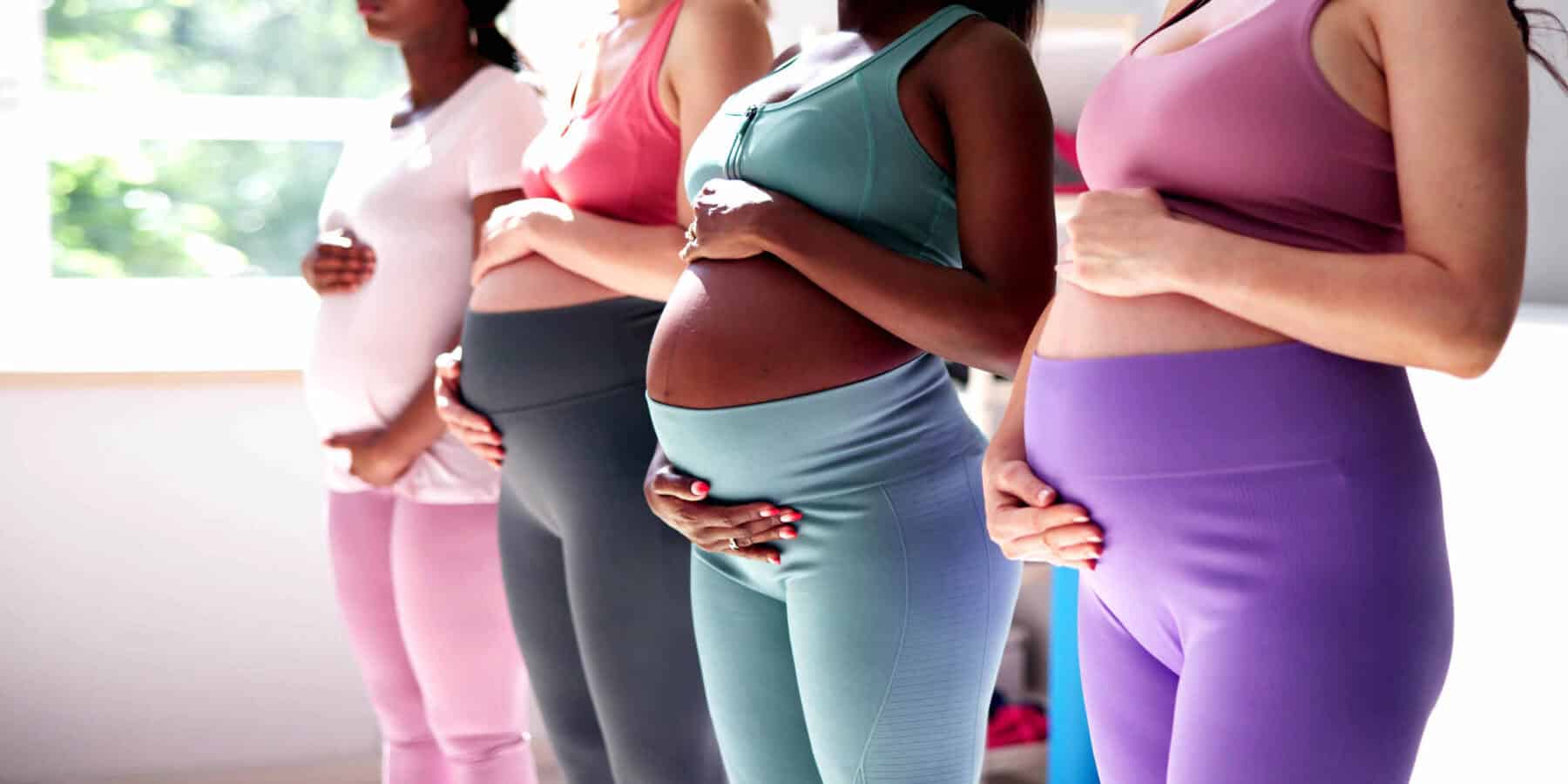 Four pregnant women holding their bellies.