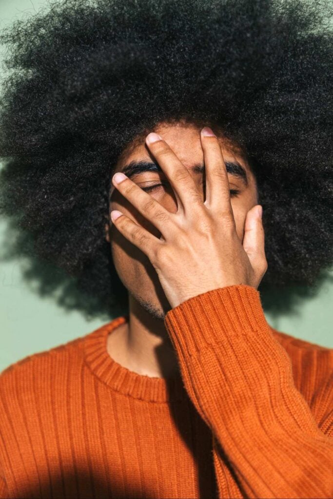 Image of a person covering their face with their hand.