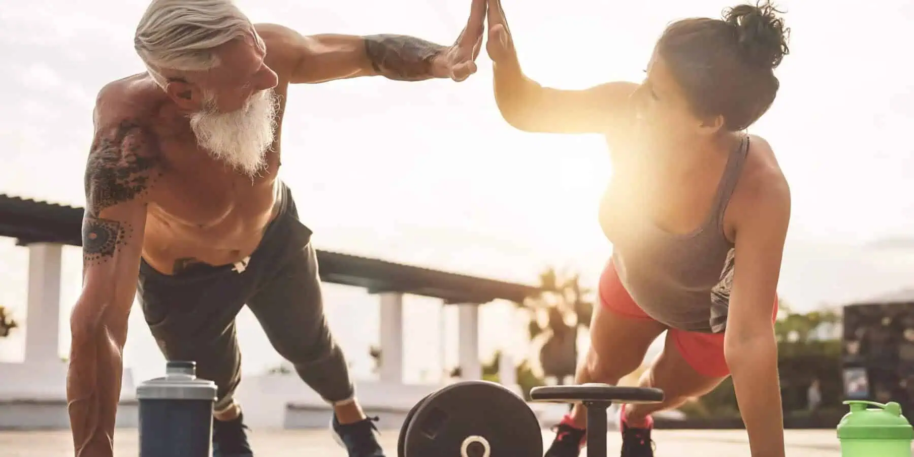 Image of two people giving each other a high five while doing a push-up