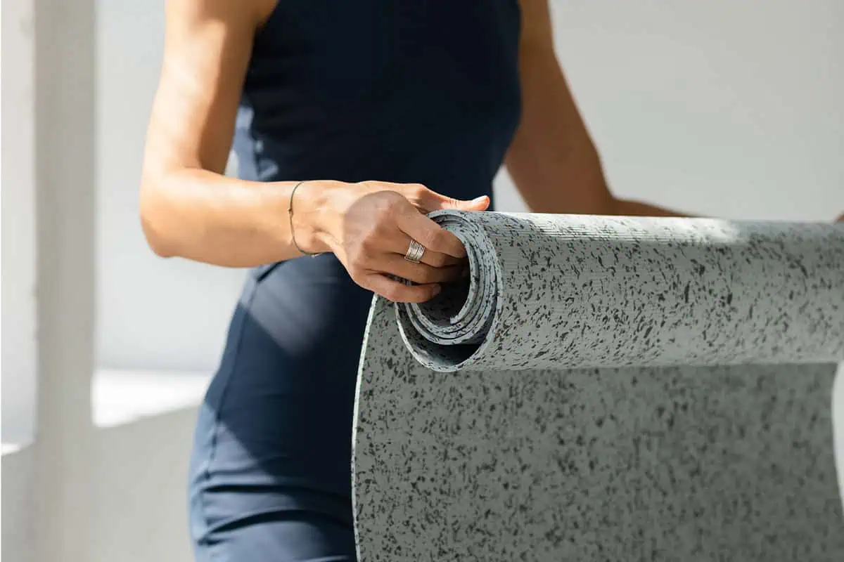 image of a woman folding a yoga mat.