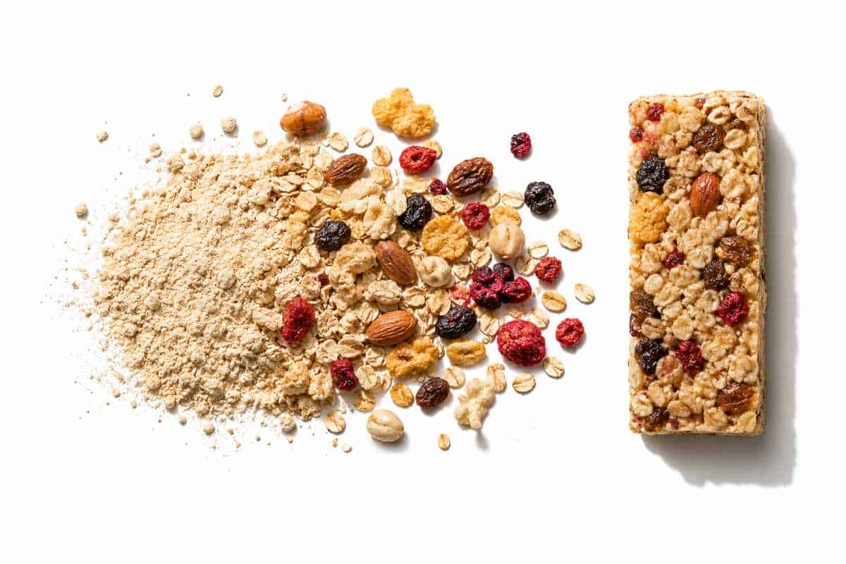 Oats, dried fruit and nuts beside a finished cereal bar