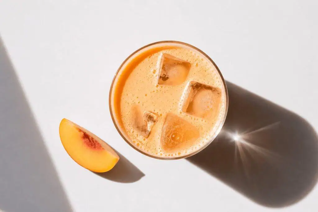 Iced peach-colored beverage with a fresh peach slice