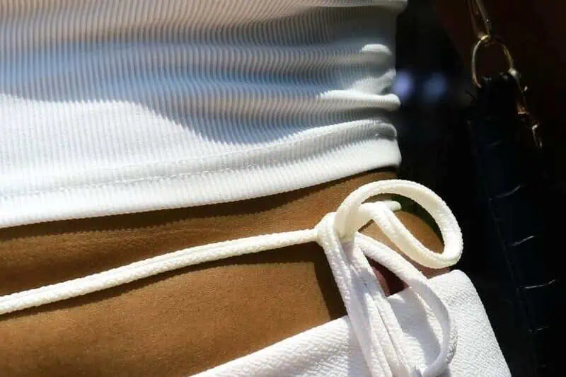 Close-up of a person wearing a white crop top and sweatpants with a drawstring.